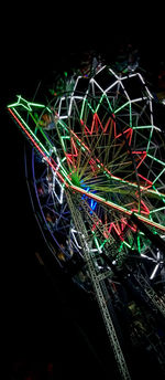 Low angle view of illuminated ferris wheel against black background