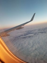 Airplane flying over cloudscape against sky during sunset