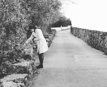 Young woman standing on street by retaining wall