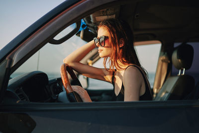 Young woman wearing sunglasses sitting in car