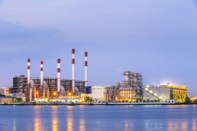 Illuminated factory against blue sky at night