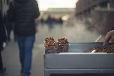 Cropped hand of man selling caramelized peanuts on street