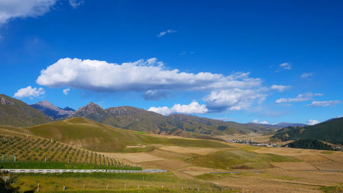 Scenic view of field and mountains against blue sky