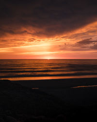 Scenic view of sea against dramatic sky during sunset