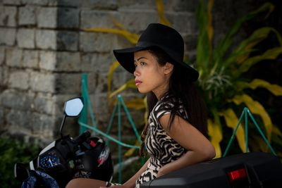 Young woman looking away while sitting on motor scooter 