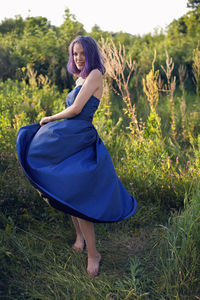 Teenage girl with dyed purple hair and a nose piercing in the grass