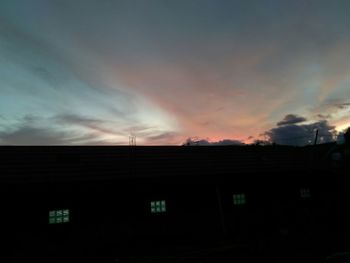 Low angle view of silhouette houses against sky at sunset