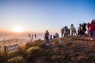 Group of people against clear sky during sunset