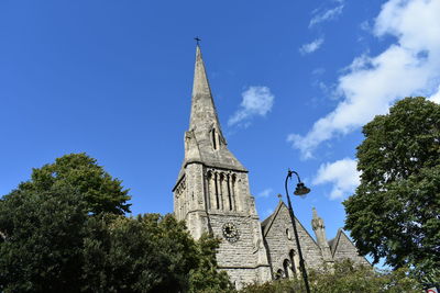 Low angle view of trees and building against sky