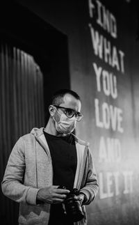 Young man wearing sunglasses standing against wall