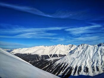 Scenic view of snowcapped mountains against blue sky