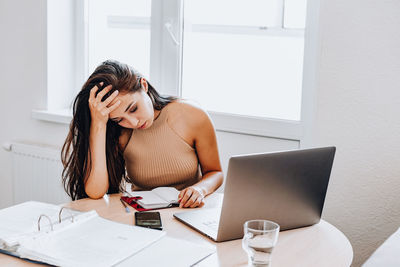 Young woman using phone while sitting on table