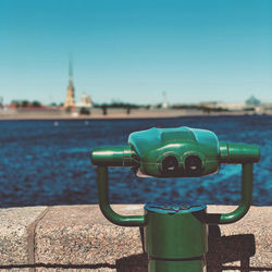 Close-up of coin-operated binoculars against blue sky