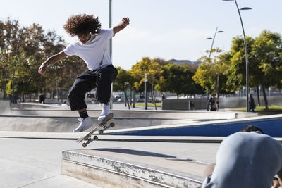 Young sportsman practicing while skateboarding at skateboard park