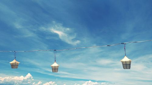 Low angle view of lighting equipment hanging against blue sky