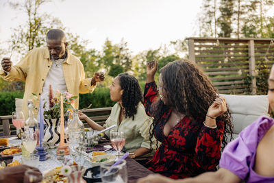 Male and female friends having fun while celebrating during dinner party in back yard