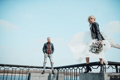 People standing on railing against sky