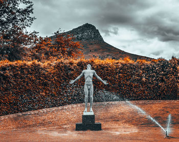 Statue by trees against sky during autumn