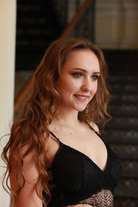 Smiling young woman wearing bikini top while standing indoors