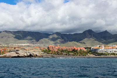 Scenic view of sea by townscape against sky