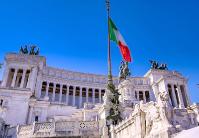 Low angle view of statues on building against blue sky