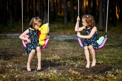 Cute girls sitting on swing at park