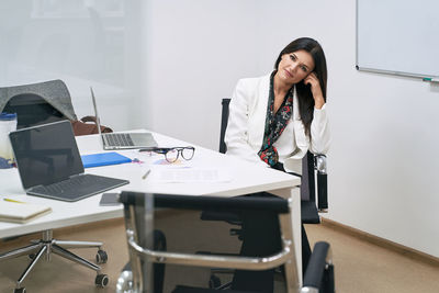 Portrait of young woman using mobile phone while sitting on table