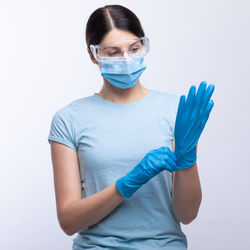 Doctor in mask wearing surgical glove against gray background