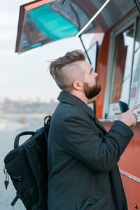 Side view portrait of young man standing outdoors