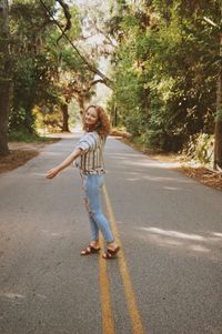 Full length portrait of woman with umbrella on road
