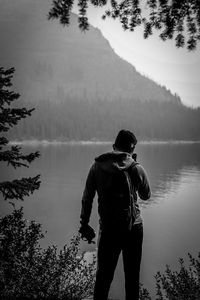 Rear view of man looking at lake in forest