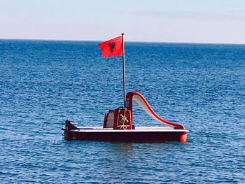 Red flag on sea against sky