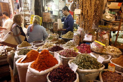 Man selling spices to women at street market