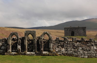 Old ruin on field against cloudy sky