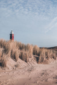 Lighthouse on beach against sky