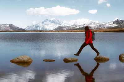 Full length of person on lake by snowcapped mountain against sky