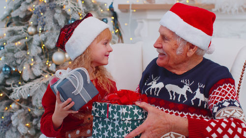 Smiling grandfather giving gift to granddaughter
