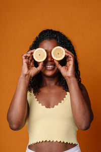 Rear view of woman holding binoculars against yellow background