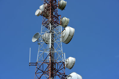 Low angle view of communications tower against clear blue sky