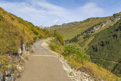 Scenic view of road leading towards mountains against sky