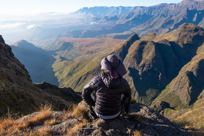 Man sitting on rock against mountains