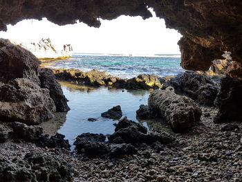 Rock formations at beach against sky