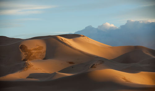 Sand dunes against sky during sunset