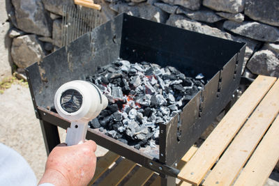 Cropped image of hand blowing coals with dryer