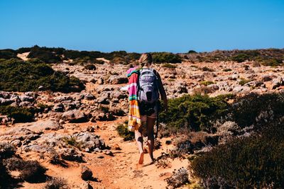 Rear view of woman walking on mountain against clear sky