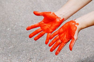 Cropped hands painted with orange paint