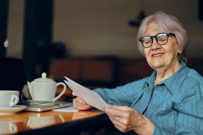Senior woman holding document at cafe
