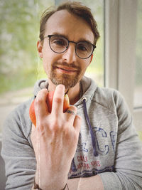 Portrait of young man holding eyeglasses