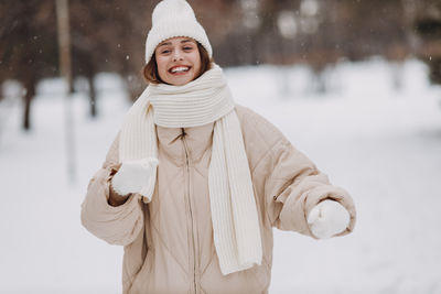 Portrait of young woman standing on snow covered field