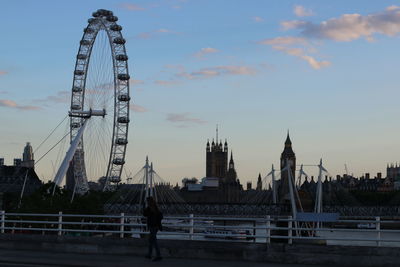 Woman walking on footpath with london eye and big ben in background